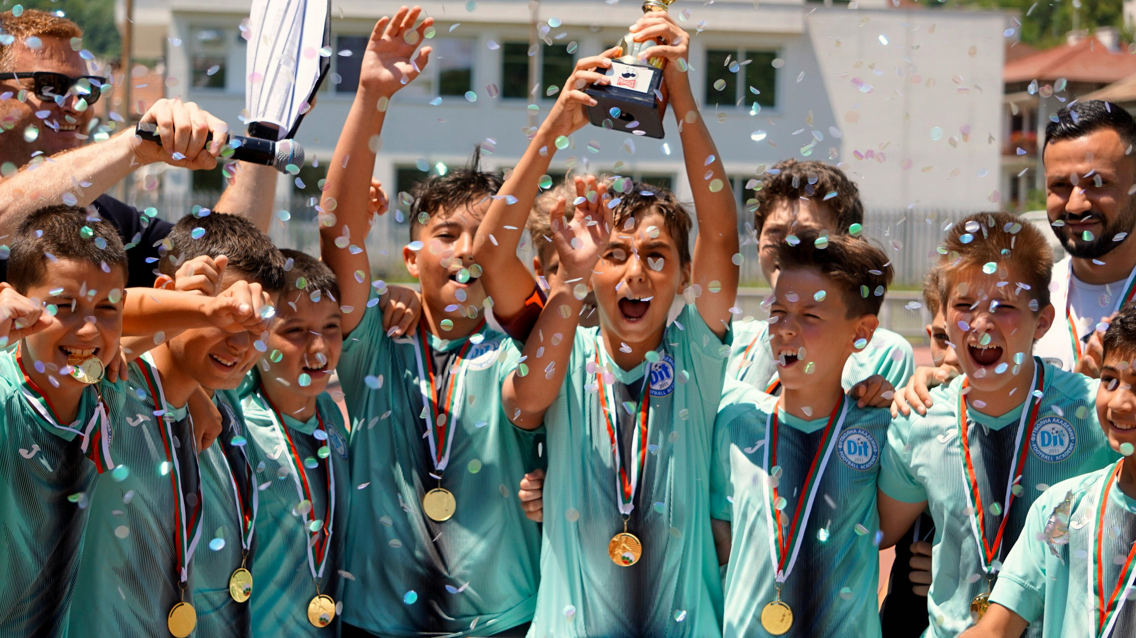 Young soccer players celebrating with trophy and medals